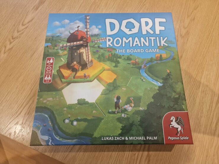 Box of Dorf Romantik: The Board Game featuring a colorful illustration of a windmill and a scenic landscape. Designed for 1-6 players aged 8 and up, with gameplay lasting 30-60 minutes. Created by Lukas Zach and Michael Palm, published by Pegasus Spiele.