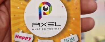 Image of the board game "Pixel," featuring a colorful box design with the title prominently displayed. The box includes playful words like "Italy," "Fish," "Space," "Happy," "Rain," and "Dream," indicating the game's creative theme. It is suitable for ages 5 and up, accommodating 1-8 players, and designed for quick play sessions of 5 minutes or more.