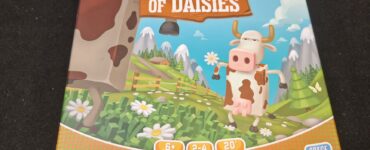 Board game "A Fistful of Daisies" featuring a cartoon cow on the cover, designed for 2-4 players aged 6 and up, with a playtime of approximately 20 minutes. The vibrant illustration includes a pastoral landscape with flowers and mountains, emphasizing a fun, family-friendly theme.