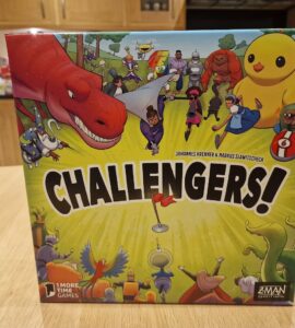 Image of the board game "Challengers!" designed by Johannes Krenner and Markus Slawitscheck, featuring colorful illustrations of various characters including a dinosaur, robots, and whimsical creatures. The game is published by Z-Man Games, showcasing an engaging and fun design suitable for family game nights.