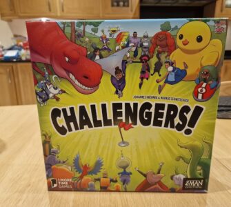 Image of the board game "Challengers!" designed by Johannes Krenner and Markus Slawitscheck, featuring colorful illustrations of various characters including a dinosaur, robots, and whimsical creatures. The game is published by Z-Man Games, showcasing an engaging and fun design suitable for family game nights.