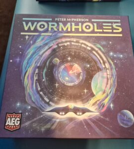 Colorful board game box for "Wormholes" by Peter McPherson, featuring a cosmic design with swirling galaxies and planets, highlighting its space-themed gameplay.