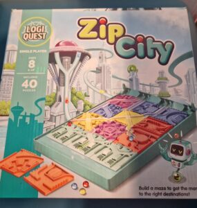 Box cover of the LogiQuest game "Zip City," featuring a futuristic cityscape, a maze-building puzzle with colorful pieces, and a robot character. Designed for single players aged 8 and up, the game includes 40 puzzles that challenge players to navigate marbles to their correct destinations.