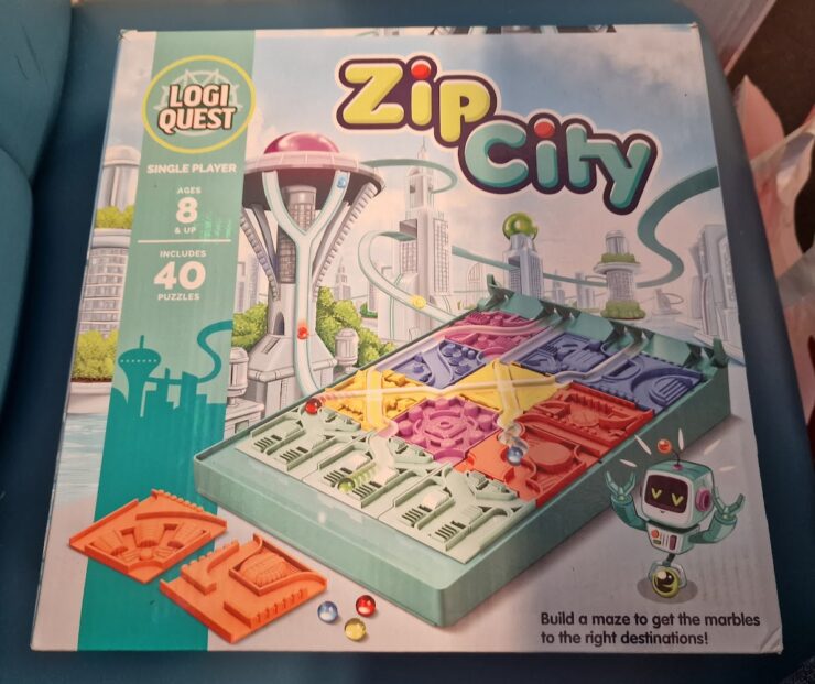 Box cover of the LogiQuest game "Zip City," featuring a futuristic cityscape, a maze-building puzzle with colorful pieces, and a robot character. Designed for single players aged 8 and up, the game includes 40 puzzles that challenge players to navigate marbles to their correct destinations.