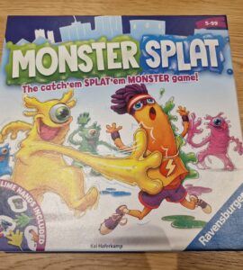 Colorful board game box for "Monster Splat" by Ravensburger, featuring playful cartoon monsters and the tagline "The catch'em SPLAT'em MONSTER game!" Includes details about the game suitable for ages 5 to 99 and highlights the inclusion of four slime hands.