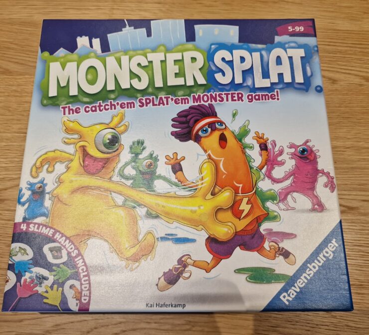 Colorful board game box for "Monster Splat" by Ravensburger, featuring playful cartoon monsters and the tagline "The catch'em SPLAT'em MONSTER game!" Includes details about the game suitable for ages 5 to 99 and highlights the inclusion of four slime hands.