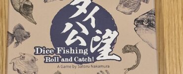 Dice Fishing game box featuring various fish illustrations, titled "Dice Fishing: Roll and Catch!" designed by Satoru Nakamura, set against a light brown background.