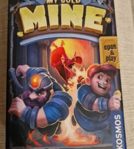 Board game box for "My Gold Mine," featuring two miners in action, one with a pickaxe and the other holding a gold coin, with a dragon in the background. The vibrant artwork showcases a fantasy theme, emphasizing adventure and treasure hunting.