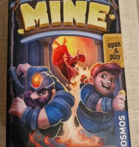 Board game box for "My Gold Mine," featuring two miners in action, one with a pickaxe and the other holding a gold coin, with a dragon in the background. The vibrant artwork showcases a fantasy theme, emphasizing adventure and treasure hunting.