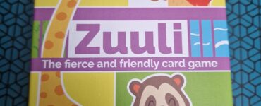 Colorful box of the card game "Zuuli," featuring playful animal illustrations including a giraffe, sloth, lion, and more. The design highlights that the game is suitable for ages 8 and up, supports 1 to 6 players, and has a playtime of approximately 15 minutes.