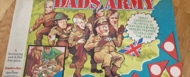 Box cover of the board game "Dad's Army," featuring colorful illustrations of characters in military attire, including a soldier with a rifle and others in various poses. The design includes the British flag and playful text, highlighting the game's theme of humor and strategy. Ideal for fans of classic British television and board games.