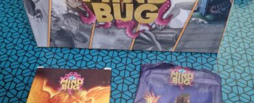 Box set of the card game "Mind Bug" featuring the main game box, a "First Contact" expansion pack, and a "2022 Promo Pack." The game combines strategy and fantasy elements, showcasing vibrant artwork of various characters and creatures.