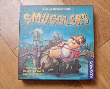 Board game box for "Smugglers," featuring colorful artwork and characters involved in the game of smuggling sweets and sour treats. Published by Kosmos, designed by Klaus and Benjamin Teuber.