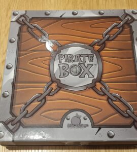 Pirate Box board game packaging featuring a wooden design with chains and a circular logo, designed for family-friendly gameplay and adventure-themed fun.