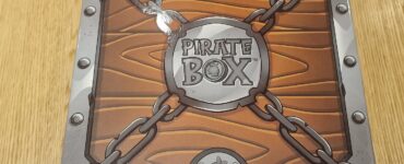Pirate Box board game packaging featuring a wooden design with chains and a circular logo, designed for family-friendly gameplay and adventure-themed fun.