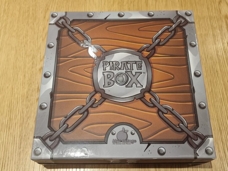 Pirate Box board game packaging featuring a wooden design with chains and a circular logo, designed for family-friendly gameplay and adventure-themed fun.