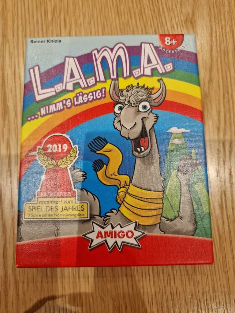 Colorful board game box for L.A.M.A. by Reiner Knizia, featuring a cartoon llama and a rainbow background. The box highlights the game's age recommendation of 8+, its nomination for the Spiel des Jahres award in 2019, and the logo of Amigo Spiele.