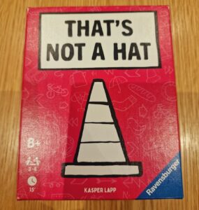 Box of the game "That's Not a Hat" by Kasper Lapp, featuring a playful design with a traffic cone illustration on a bright red background. Suitable for ages 8 and up, designed for 3 to 8 players with an estimated playtime of 15 minutes.