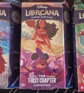 Disney Lorcana trading card game starter decks featuring characters like Simba, Moana, Mickey Mouse, and Cruella de Vil. Each deck is part of "The First Chapter" series, suitable for ages 8 and up.