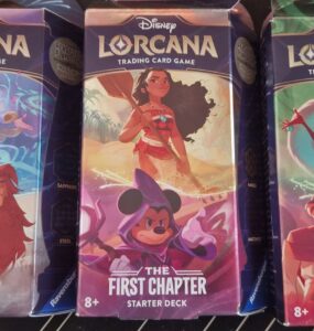 Disney Lorcana trading card game starter decks featuring characters like Simba, Moana, Mickey Mouse, and Cruella de Vil. Each deck is part of "The First Chapter" series, suitable for ages 8 and up.