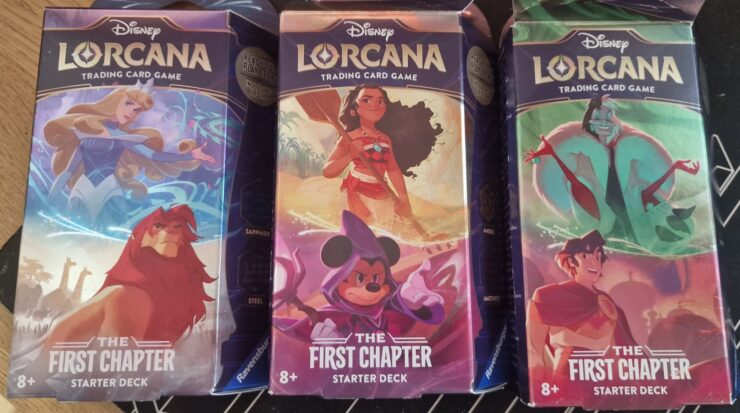 Disney Lorcana trading card game starter decks featuring characters like Simba, Moana, Mickey Mouse, and Cruella de Vil. Each deck is part of "The First Chapter" series, suitable for ages 8 and up.