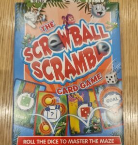 Colorful packaging of "Screwball Scramble" card game featuring playful graphics, instructions to roll dice and navigate a maze, designed for family fun and entertainment.