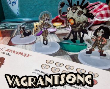 Vagrantsong tabletop game components featuring colorful acrylic character standees, including a dog, a female character with a weapon, and a quirky monster, set against a game board with dice and a character sheet.