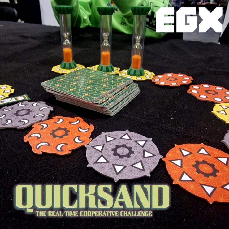 Image of the board game "Quicksand" displayed at EGX, featuring colorful game pieces including hexagonal tokens and hourglasses, highlighting the cooperative gameplay and real-time challenge elements.