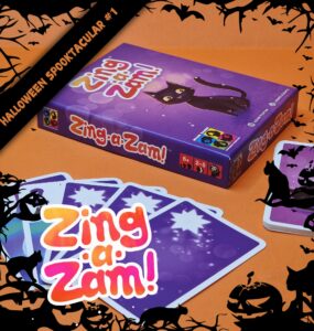 Halloween-themed game "Zing-a-Zam!" displayed with colorful cards and a purple box featuring a playful black cat, suitable for 2-5 players aged 6 and up. Perfect for festive gatherings and family game nights.