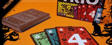 Colorful card game "Trio" displayed on an orange background, featuring a stack of cards and the game box. The cards showcase vibrant designs with numbers, perfect for family game nights. Ideal for ages 7 and up, emphasizing fun and strategy. Halloween-themed decorations enhance the festive atmosphere.