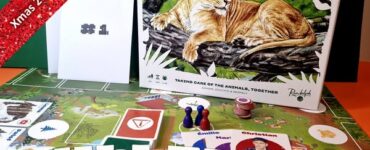 Miller Zoo cooperative board game displayed on a colorful game board, featuring a lion illustration on the box cover. The image includes game components like player tokens and character cards, along with a festive banner indicating "Xmas 2023 Holiday Marathon #4."
