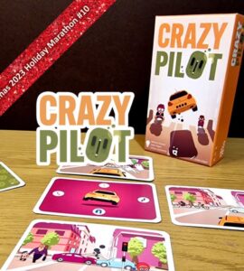 Image of the board game "Crazy Pilot" displayed on a wooden table, featuring the game's colorful box and several gameplay cards illustrating various city scenes with vehicles and pedestrians. The image promotes the Xmas 2023 Holiday Marathon event.
