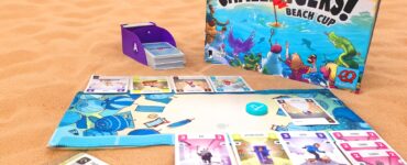 Colorful board game "Challengers! Beach Cup" displayed on sandy beach background, featuring game components like character cards, a scoring sheet, and a card holder. Ideal for family and friends' game nights, emphasizing fun and strategy.