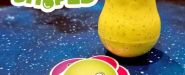 Colorful pear-shaped toy with googly eyes next to vibrant game cards on a starry background, showcasing the playful design of the "Pear Shaped" game.