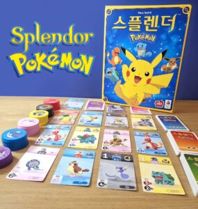 Image of the board game "Splendor: Pokémon" featuring colorful cards and tokens on a wooden table. The game box showcases Pikachu and other Pokémon characters, highlighting the combination of strategy and Pokémon themes. Ideal for family game nights and Pokémon fans.