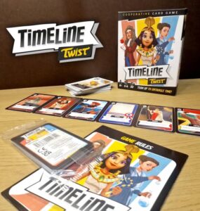 Cooperative card game "Timeline Twist" displayed on a wooden surface, featuring the game box, cards laid out in sequence, and rule booklet. The game encourages teamwork to navigate historical events, suitable for 2-8 players aged 8 and up.