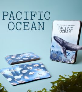 Pacific Ocean-themed card game featuring beautifully illustrated cards showcasing marine life, including shells and a whale, alongside the game box. Ideal for ocean enthusiasts and educational purposes.