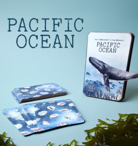 Pacific Ocean-themed card game featuring beautifully illustrated cards showcasing marine life, including shells and a whale, alongside the game box. Ideal for ocean enthusiasts and educational purposes.