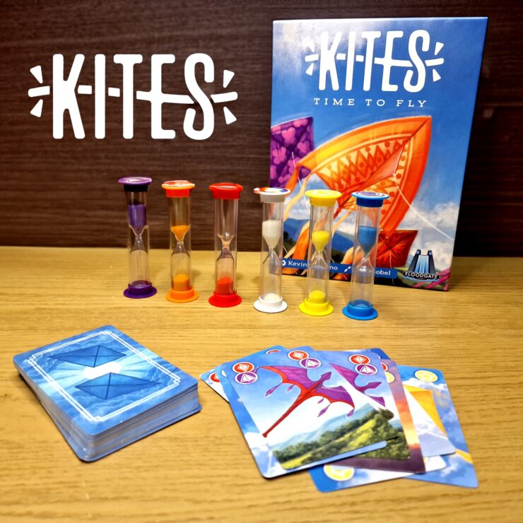 Colorful game components for "Kites: Time to Fly," featuring hourglasses and playing cards on a wooden surface. The game box displays vibrant kite artwork, emphasizing a fun and engaging family game experience.