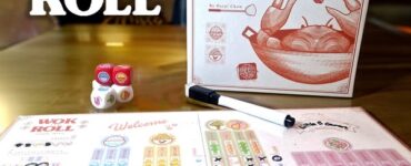 Wok and Roll board game displayed on a wooden table, featuring the game box, colorful dice, and player score sheets. The design highlights modern Asian themes and gameplay elements, suitable for family and friends.