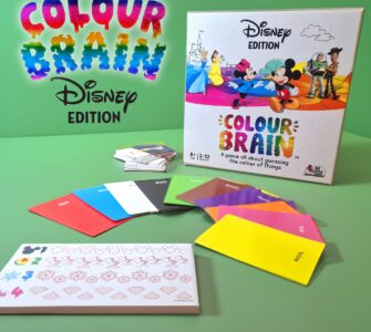 Colour Brain Disney Edition board game displayed on a green background, featuring colorful question cards, answer cards, and a game box with iconic Disney characters. Suitable for 2 to 12 players aged 8 and up, this game challenges players to guess the colors of various Disney-themed items.