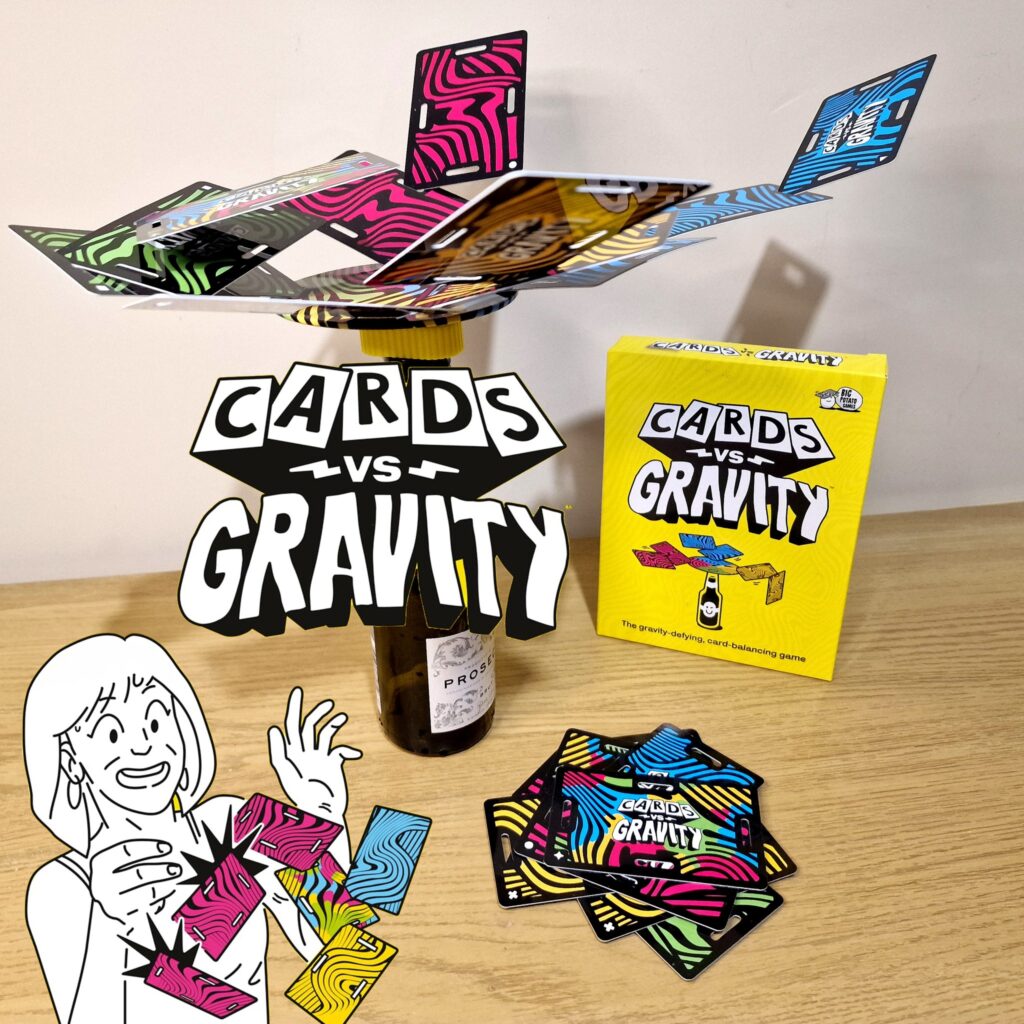 Image of the game "Cards vs Gravity," featuring colorful cards balanced on a bottle, with the game box displayed on a wooden surface. A cartoon character excitedly holds a card, showcasing the fun and challenging nature of this gravity-defying card balancing game.