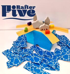 Colorful game setup for "Rafter Five," featuring a blue box with wooden animal figures and vibrant building pieces scattered around.