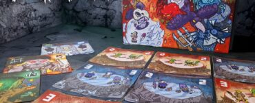Colorful board game "Eter" with illustrated cards spread out on a textured surface, featuring various characters and vibrant artwork. The game box is prominently displayed in the background, showcasing its creative design. Ideal for tabletop gaming enthusiasts.