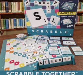 Scrabble Together game box displayed with game pieces and board, featuring colorful tiles, goal cards, and letters, set against a library background. Perfect for family game nights and word enthusiasts.