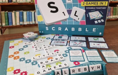 Scrabble Together game box displayed with game pieces and board, featuring colorful tiles, goal cards, and letters, set against a library background. Perfect for family game nights and word enthusiasts.