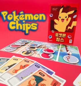 Colorful display of Pokémon Chips game featuring Pikachu on the box, with game pieces and character cards laid out on a vibrant pink background. Ideal for Pokémon fans and collectors, showcasing interactive gameplay elements.