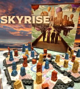 Colorful game components of the board game Skyrise are displayed on a vibrant game board, showcasing various building pieces in different colors and heights. The game's artwork, featuring a futuristic cityscape with hot air balloons and characters, is prominently featured in the background.