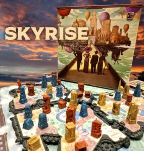 Colorful game components of the board game Skyrise are displayed on a vibrant game board, showcasing various building pieces in different colors and heights. The game's artwork, featuring a futuristic cityscape with hot air balloons and characters, is prominently featured in the background.