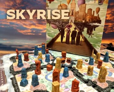 Colorful game components of the board game Skyrise are displayed on a vibrant game board, showcasing various building pieces in different colors and heights. The game's artwork, featuring a futuristic cityscape with hot air balloons and characters, is prominently featured in the background.